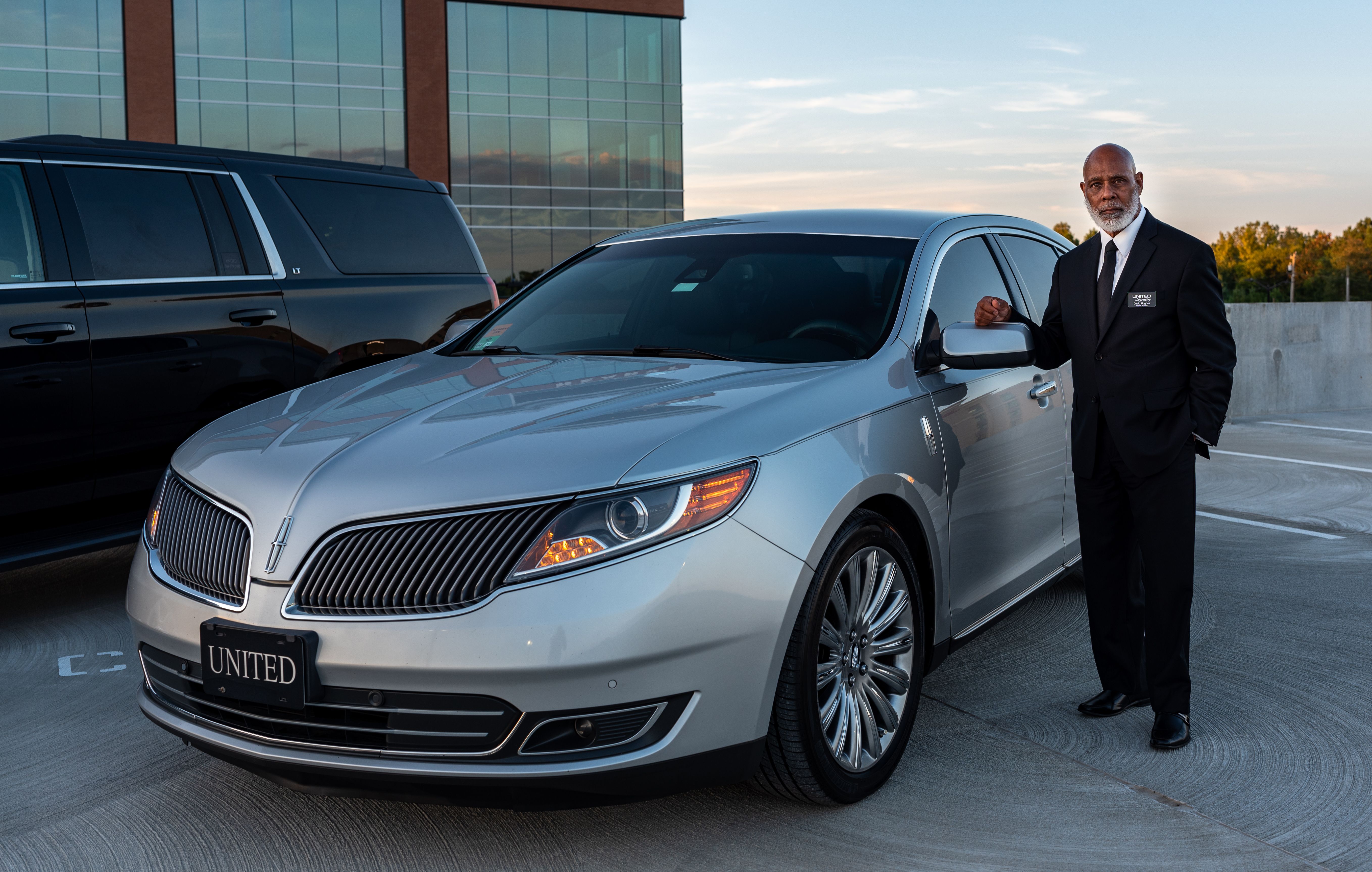 Chauffeur beside a car, ready for a business traveler